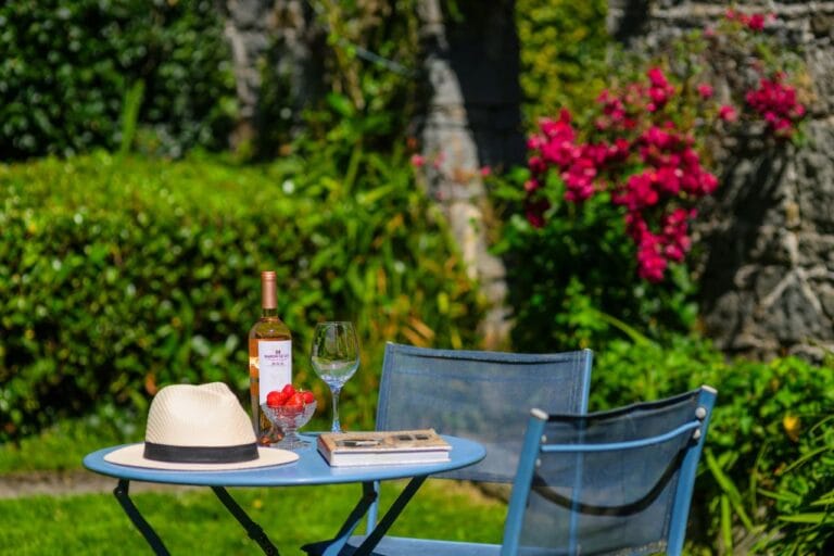 Table and tow chairs with wine, sun hat and book